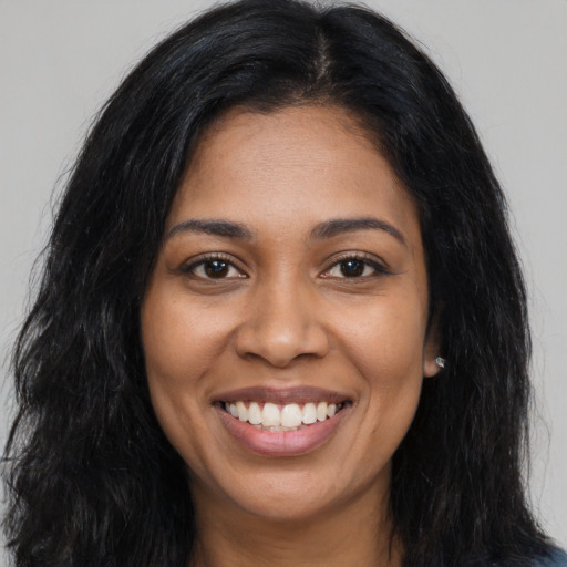 Joyful black young-adult female with long  brown hair and brown eyes
