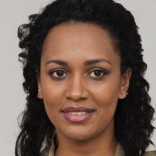 Joyful black young-adult female with long  black hair and brown eyes