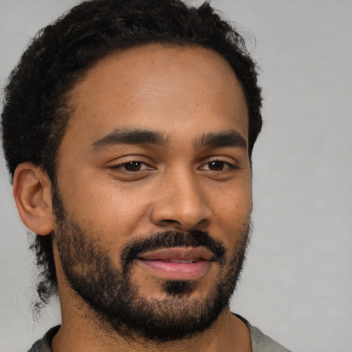 Joyful black young-adult male with short  black hair and brown eyes