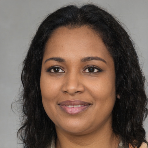 Joyful black young-adult female with long  brown hair and brown eyes