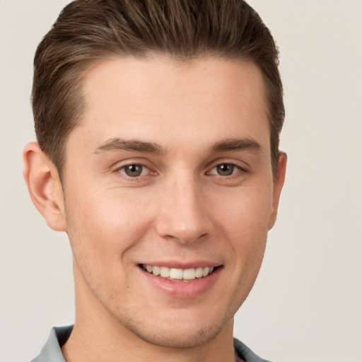 Joyful white young-adult male with short  brown hair and grey eyes