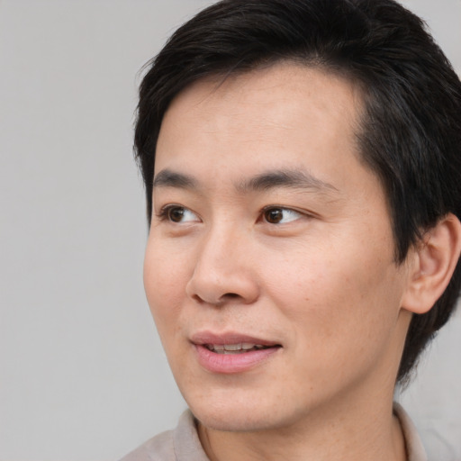 Joyful asian young-adult male with short  black hair and brown eyes