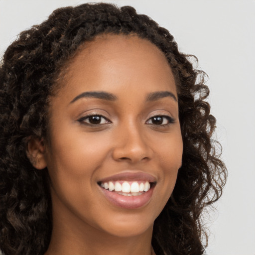 Joyful black young-adult female with long  brown hair and brown eyes