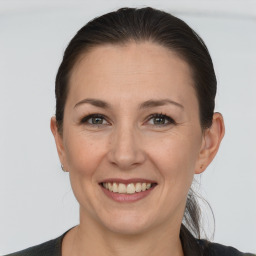 Joyful white adult female with long  brown hair and grey eyes