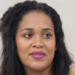 Joyful black adult female with long  brown hair and brown eyes