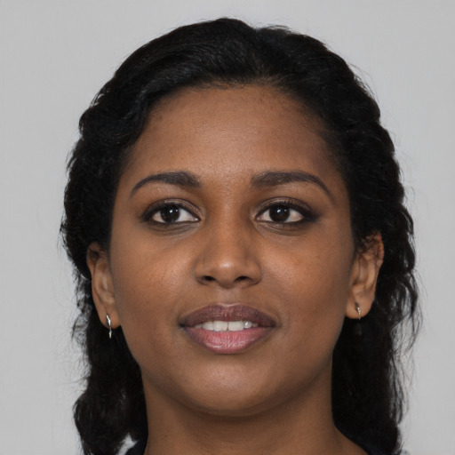 Joyful black young-adult female with long  black hair and brown eyes