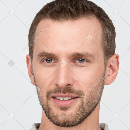 Joyful white young-adult male with short  brown hair and grey eyes