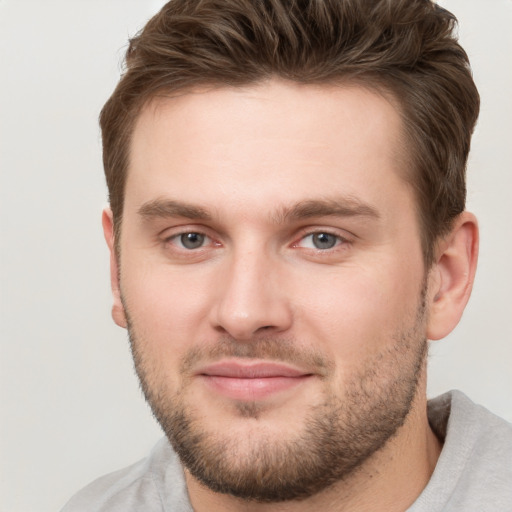 Joyful white young-adult male with short  brown hair and grey eyes