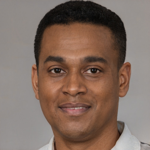 Joyful black young-adult male with short  black hair and brown eyes