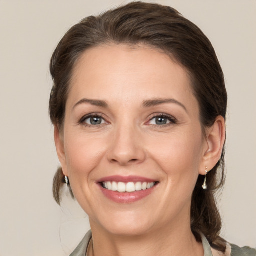 Joyful white young-adult female with medium  brown hair and grey eyes