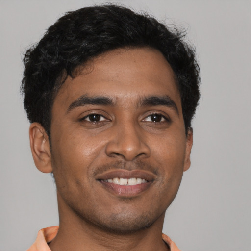 Joyful black young-adult male with short  brown hair and brown eyes