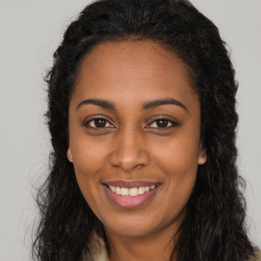 Joyful black young-adult female with long  black hair and brown eyes