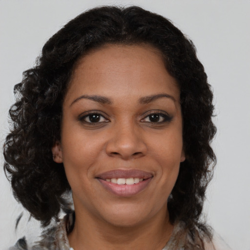 Joyful black young-adult female with long  brown hair and brown eyes