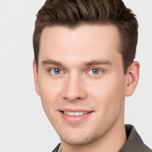 Joyful white young-adult male with short  brown hair and grey eyes