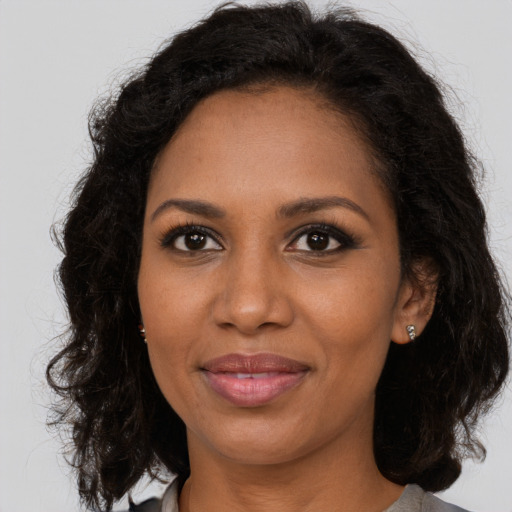 Joyful black adult female with long  brown hair and brown eyes
