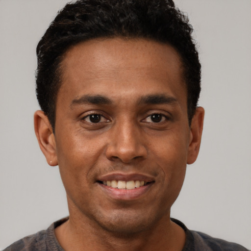 Joyful black young-adult male with short  brown hair and brown eyes