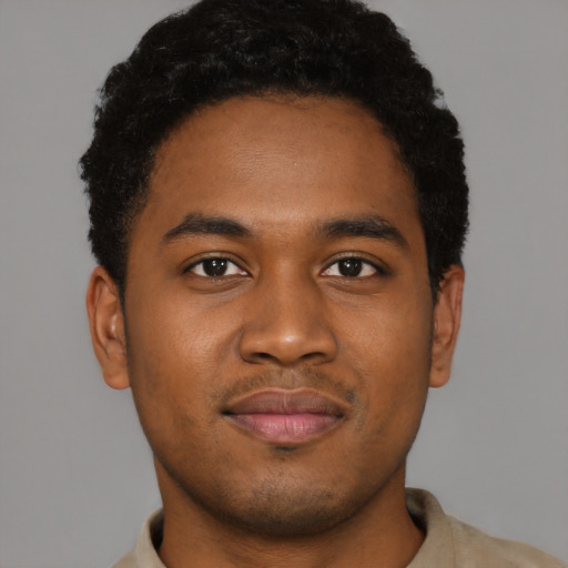 Joyful black young-adult male with short  brown hair and brown eyes