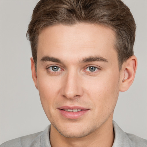 Joyful white young-adult male with short  brown hair and grey eyes