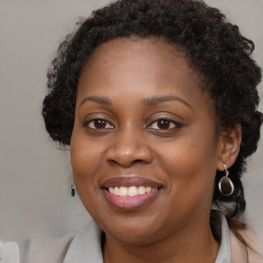 Joyful black young-adult female with long  brown hair and brown eyes