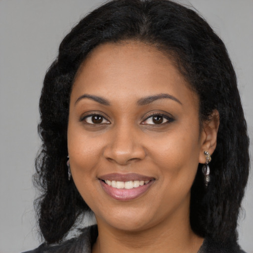 Joyful black young-adult female with long  brown hair and brown eyes