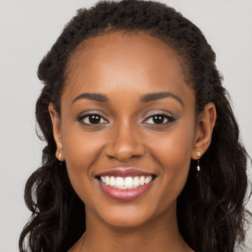 Joyful black young-adult female with long  brown hair and brown eyes