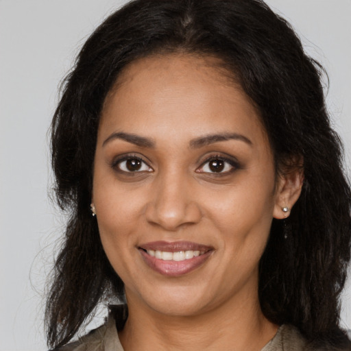 Joyful black young-adult female with long  brown hair and brown eyes