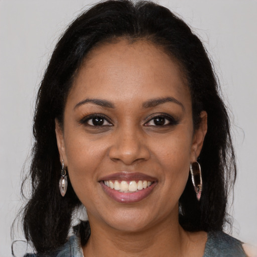 Joyful black young-adult female with long  brown hair and brown eyes