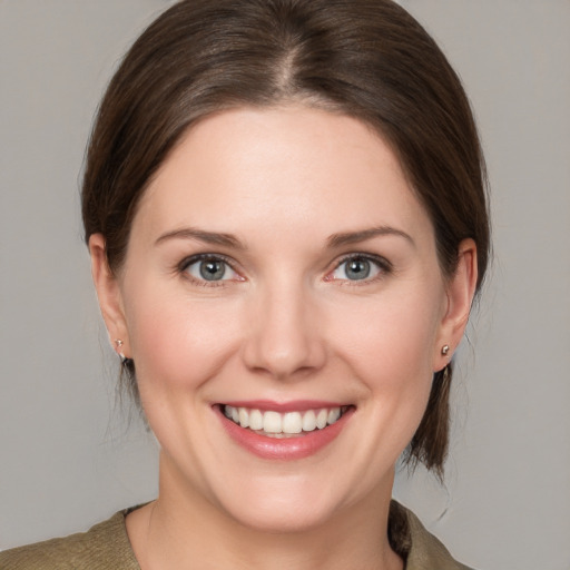 Joyful white young-adult female with medium  brown hair and grey eyes