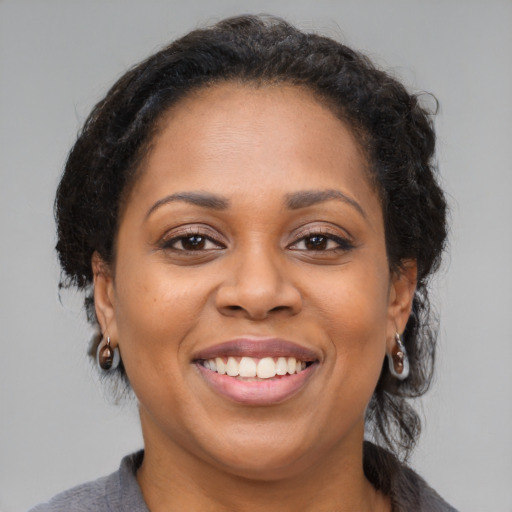 Joyful black adult female with medium  brown hair and brown eyes
