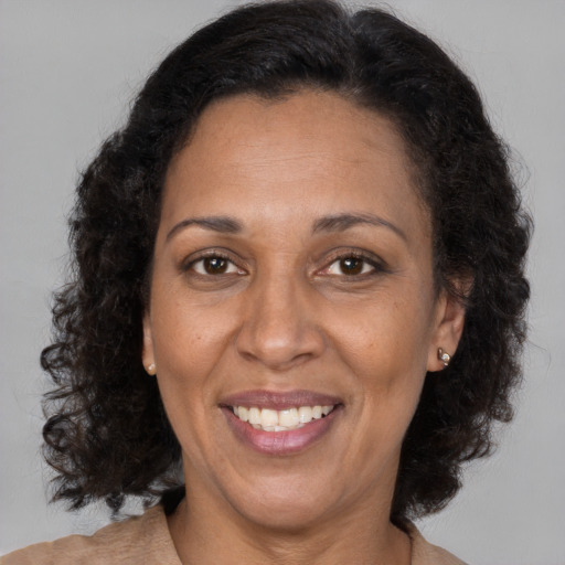 Joyful black adult female with long  brown hair and brown eyes