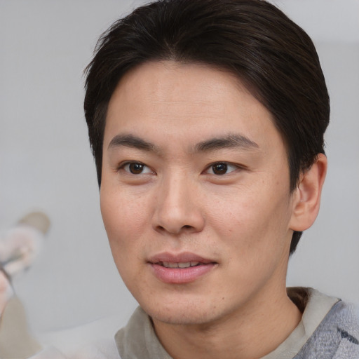 Joyful asian young-adult male with short  brown hair and brown eyes