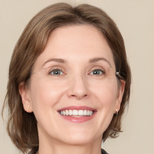 Joyful white adult female with medium  brown hair and grey eyes