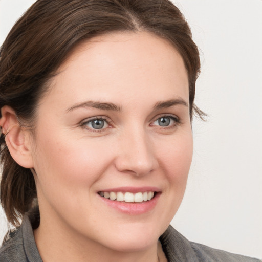 Joyful white young-adult female with medium  brown hair and grey eyes