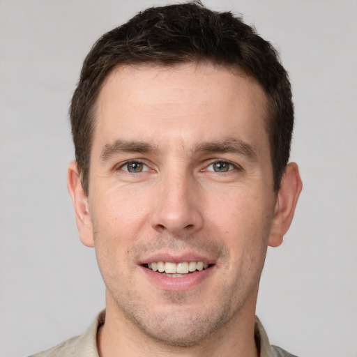 Joyful white young-adult male with short  brown hair and grey eyes