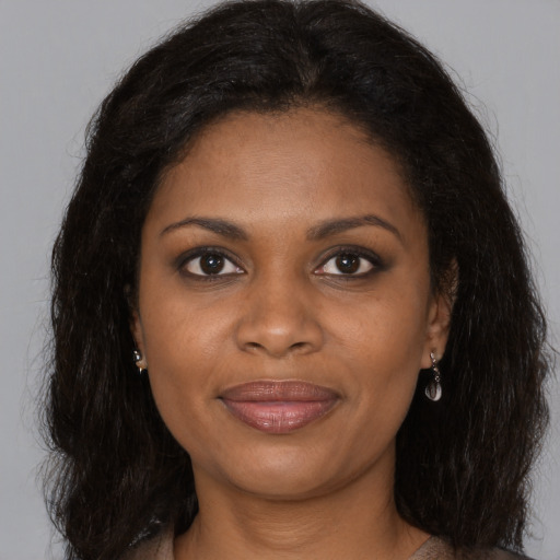 Joyful black young-adult female with long  brown hair and brown eyes
