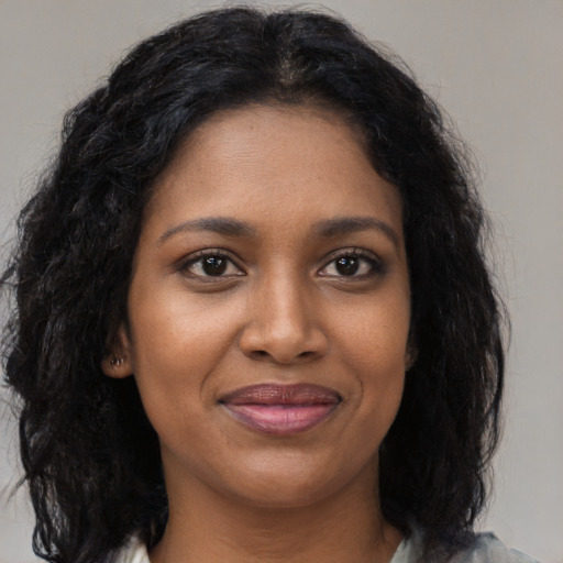 Joyful black young-adult female with long  brown hair and brown eyes