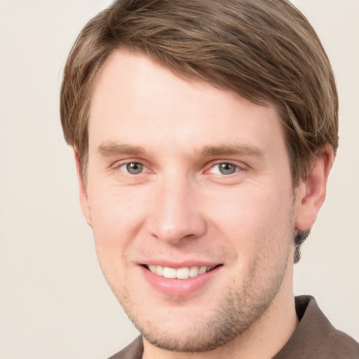 Joyful white young-adult male with short  brown hair and grey eyes