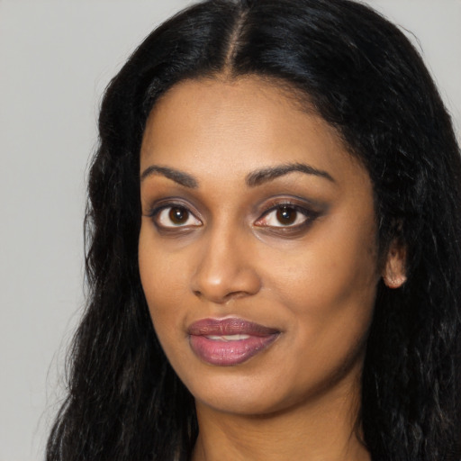 Joyful black young-adult female with long  black hair and brown eyes