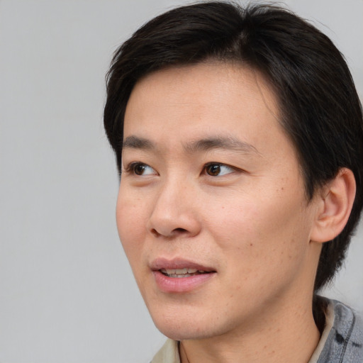 Joyful asian adult male with short  brown hair and brown eyes