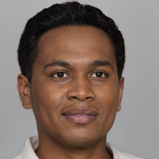 Joyful black young-adult male with short  brown hair and brown eyes