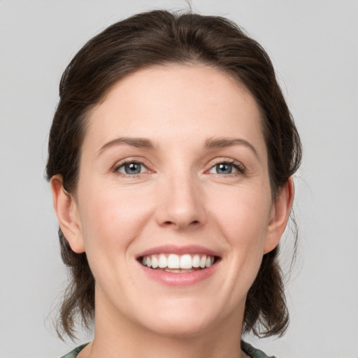 Joyful white young-adult female with medium  brown hair and green eyes