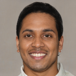 Joyful latino young-adult male with short  black hair and brown eyes