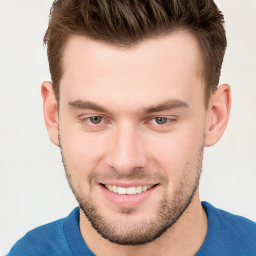 Joyful white young-adult male with short  brown hair and grey eyes