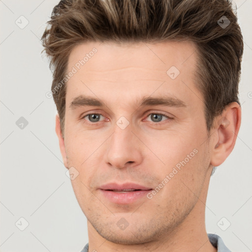 Joyful white young-adult male with short  brown hair and grey eyes