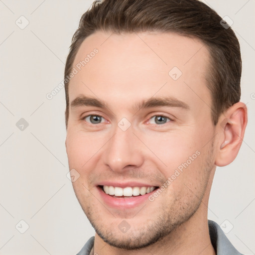 Joyful white young-adult male with short  brown hair and grey eyes