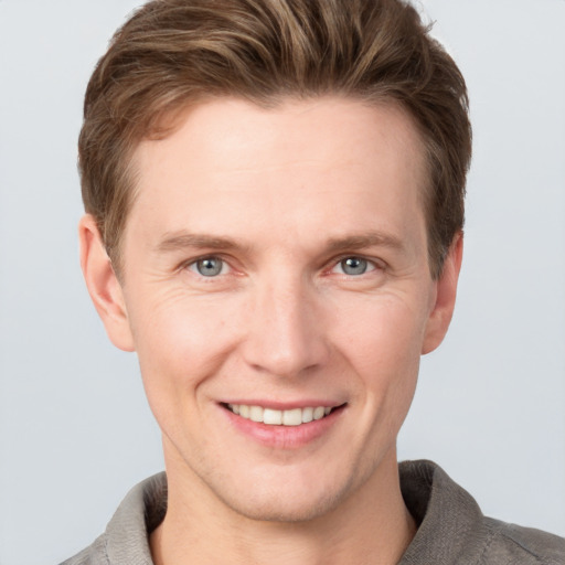 Joyful white young-adult male with short  brown hair and grey eyes