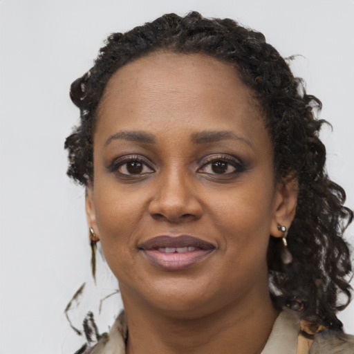 Joyful black young-adult female with long  brown hair and brown eyes