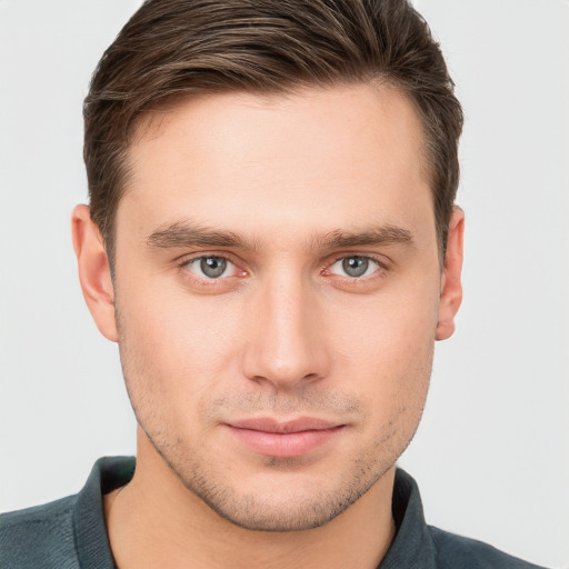 Joyful white young-adult male with short  brown hair and grey eyes