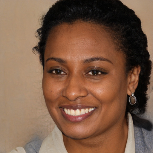 Joyful black young-adult female with short  brown hair and brown eyes