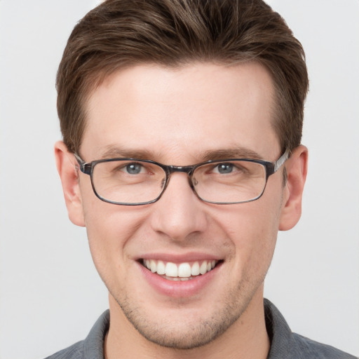 Joyful white young-adult male with short  brown hair and grey eyes